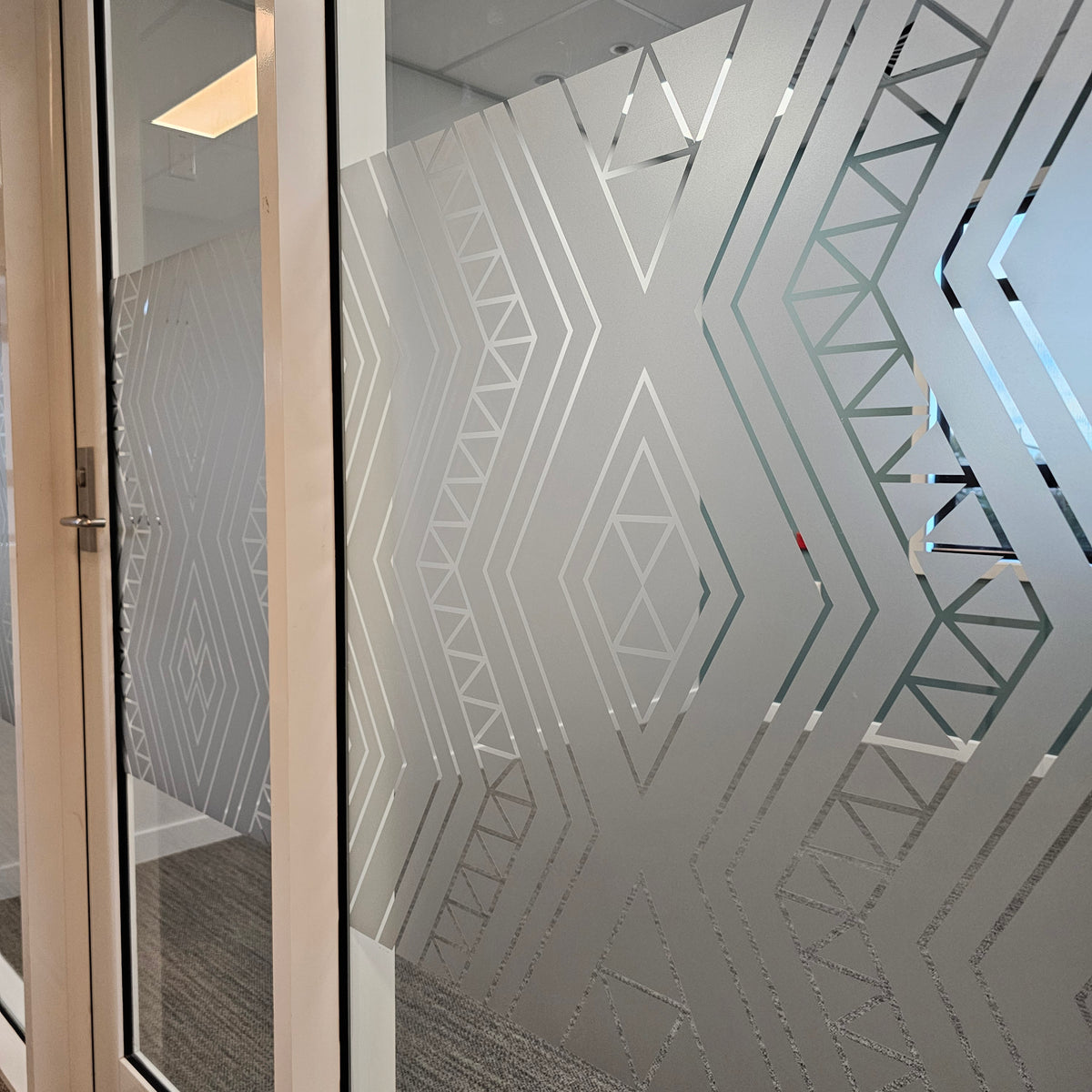 Bespoke geometric frosted film with clear cut-out details on a commercial glass partition by YDS Studio