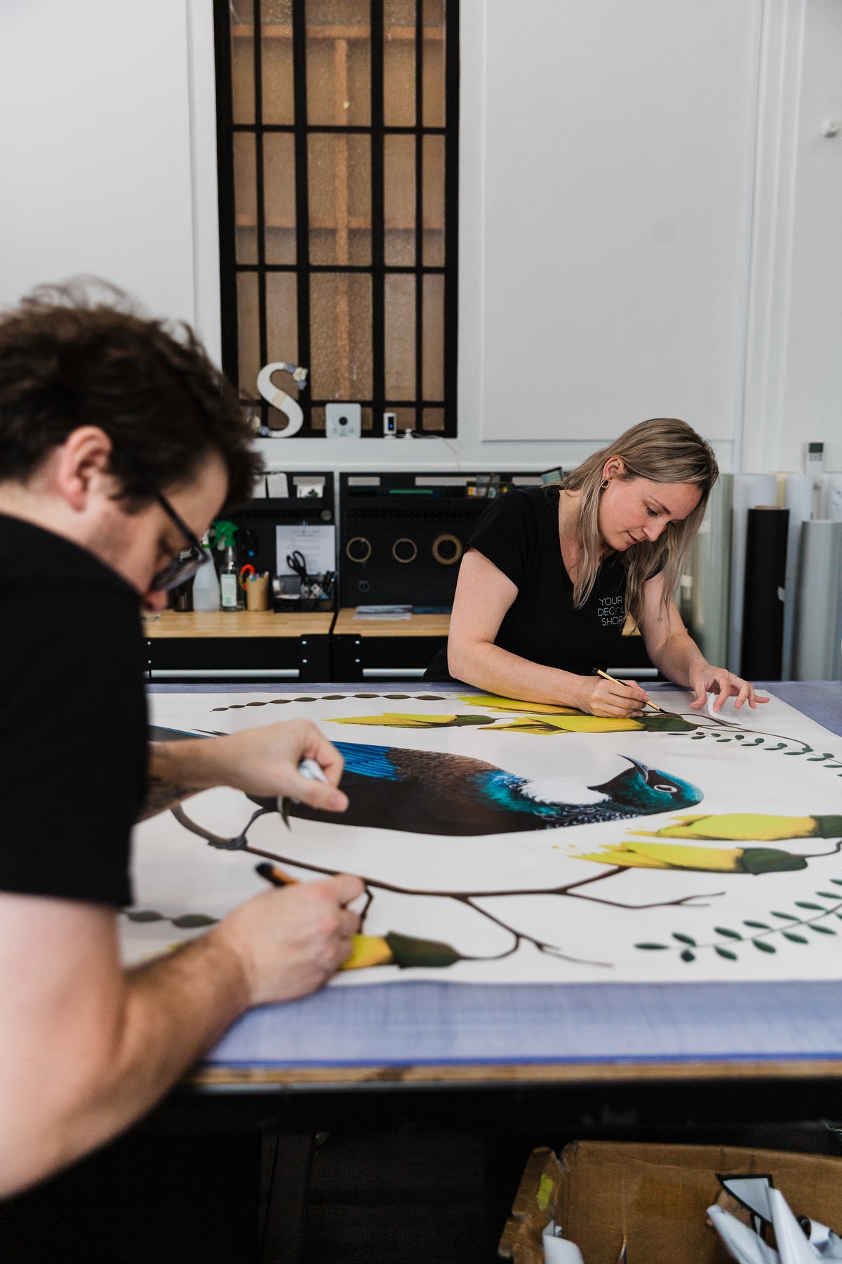 Team members working on printed wall art at the studio finishing tables