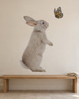 Bunny and Butterfly by Olivia Bezett, wall decal room mock-up in a room above a low timber bench.