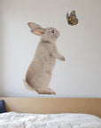 Bunny and Butterfly by Olivia Bezett, wall decal room mock-up in a bedroom above a blue bed.