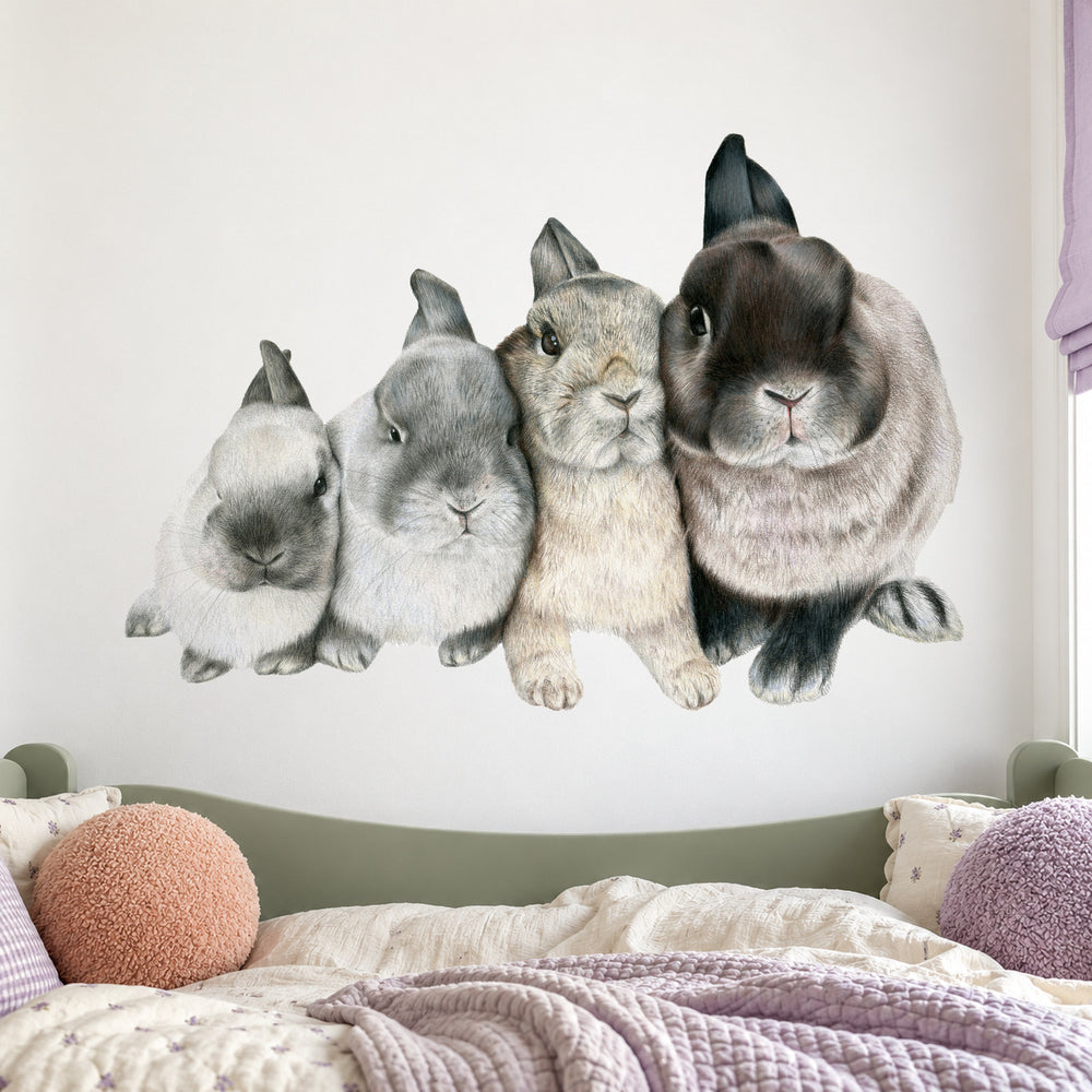Four Bunnies by Olivia Bezett, wall decal room mock-up in a bedroom above layered pink and green bedding.