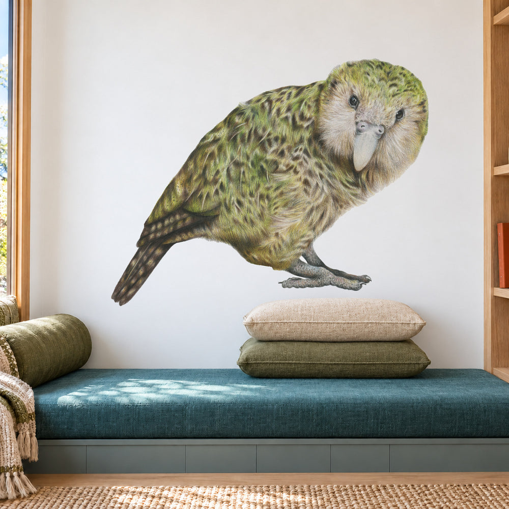 Kākāpō by Olivia Bezett, wall decal room mock-up in a reading nook above a green upholstered seat.