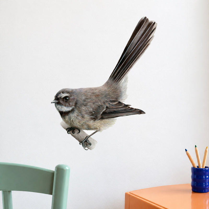 Pīwakawaka by Olivia Bezett, wall decal room mock-up in a study beside colourful stationery.