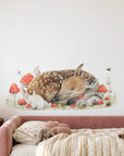 Sleeping Doe by Olivia Bezett, wall decal room mock-up in a bedroom above a pale pink bed.